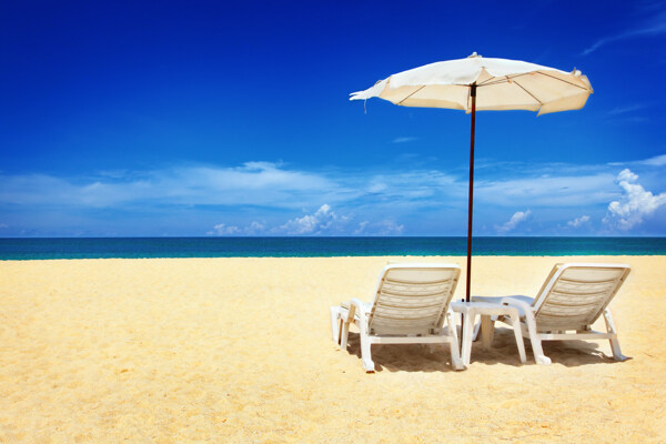 两把椅子和伞在沙滩上图片