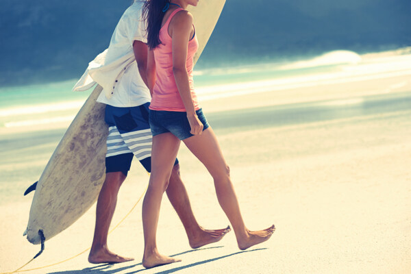 沙滩上拿着冲浪板的情侣图片