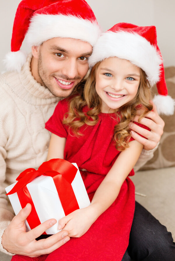 带着圣诞帽抱着礼物的男人与小女孩图片