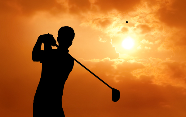 夕阳下挥动高尔夫球的男人