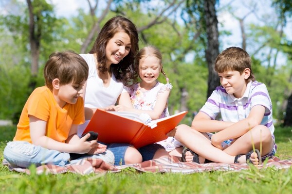 坐在草地上陪孩子看书的母亲图片