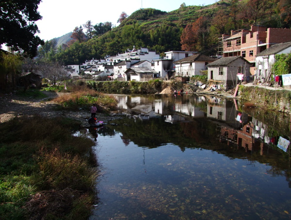 宁静的村庄景象和一条蜿蜒流淌的小河清澈见底